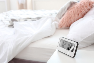 Photo of Digital alarm clock on table in bedroom. Time of day