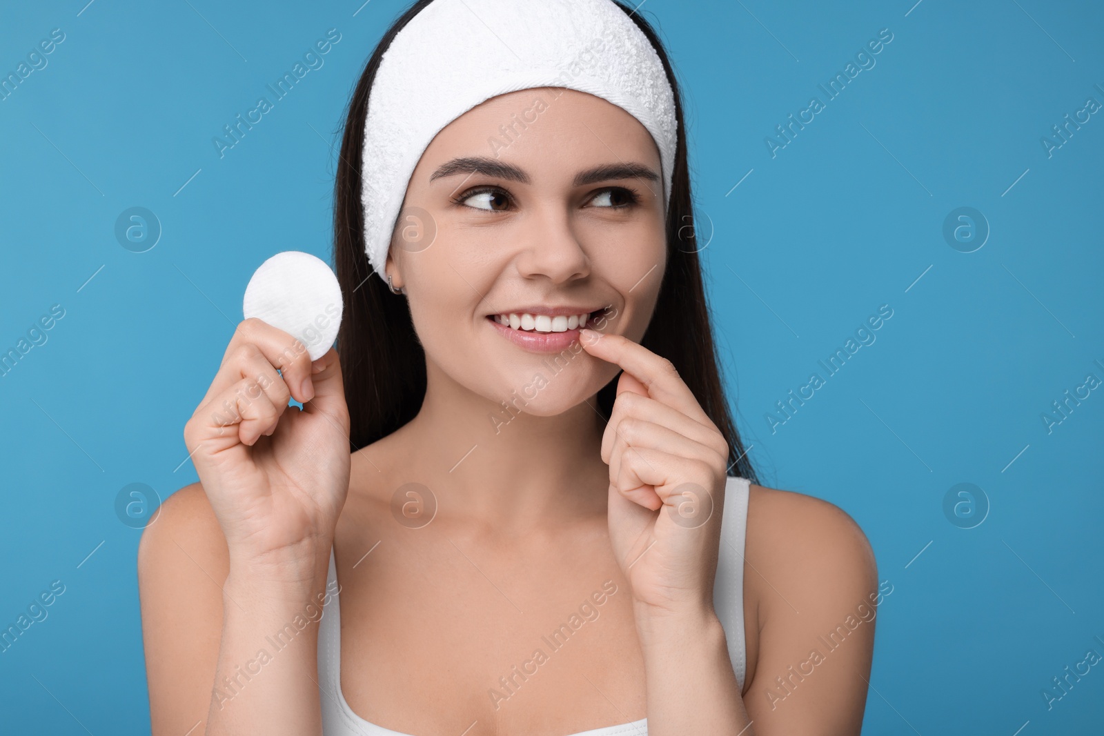 Photo of Young woman with cotton pad on light blue background