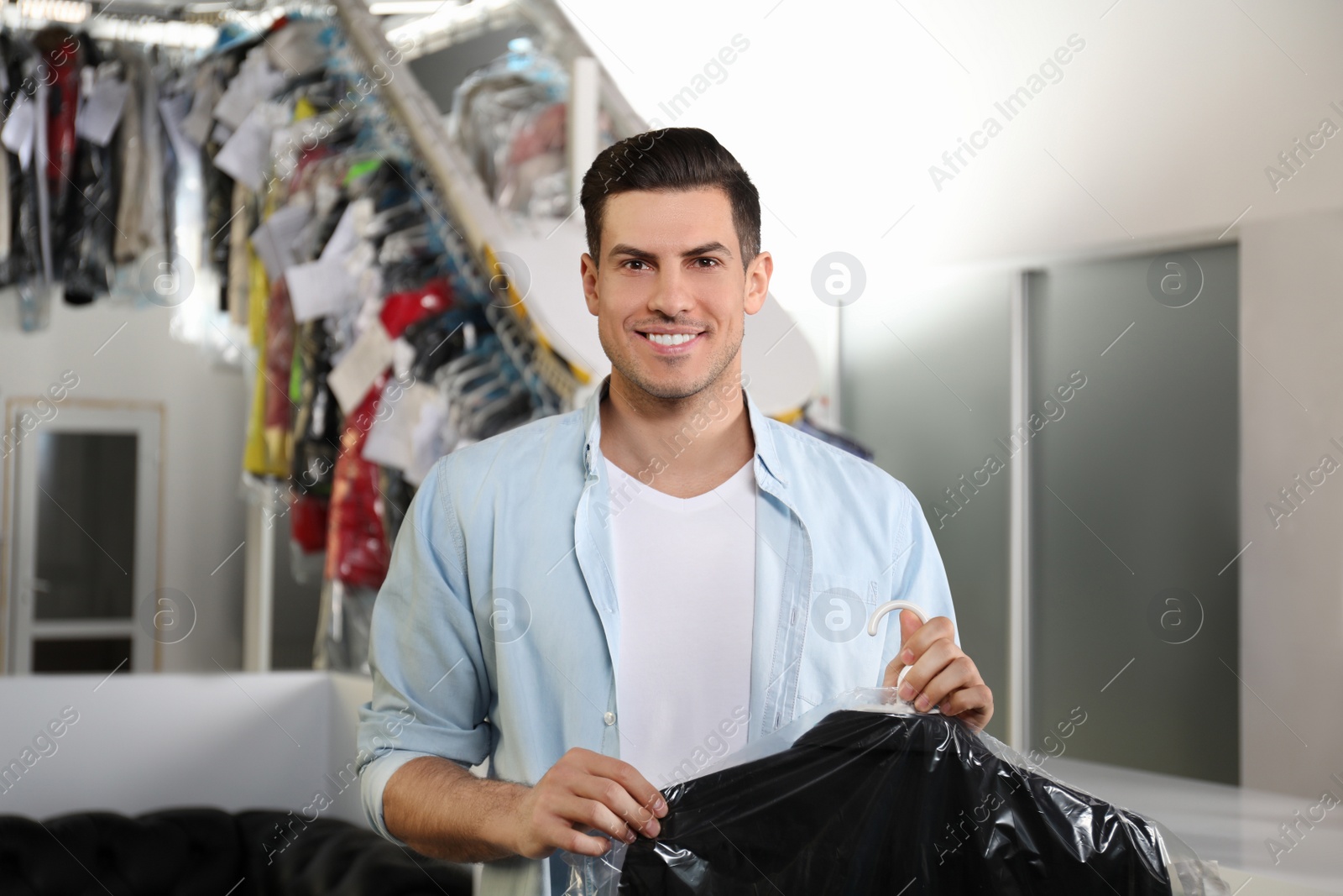 Photo of Happy client with clothes at modern dry-cleaner's