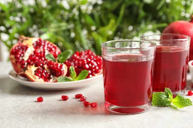 Photo of Composition with glasses of fresh pomegranate juice on table. Space for text