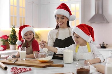 Photo of Mother with her cute little children making Christmas cookies in kitchen