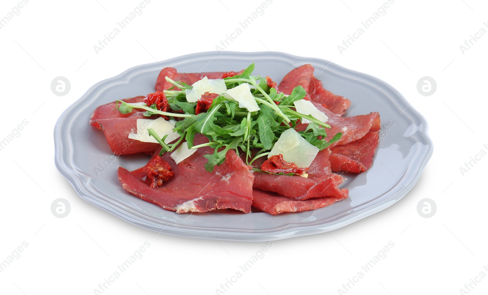 Photo of Plate of tasty bresaola salad with sun-dried tomatoes and parmesan cheese isolated on white