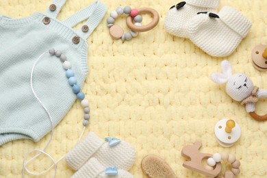 Photo of Frame of cute baby stuff on yellow knitted fabric, flat lay. Space for text