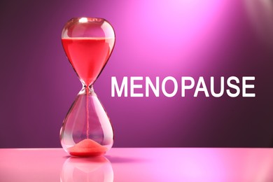 Menopause word and hourglass on purple background
