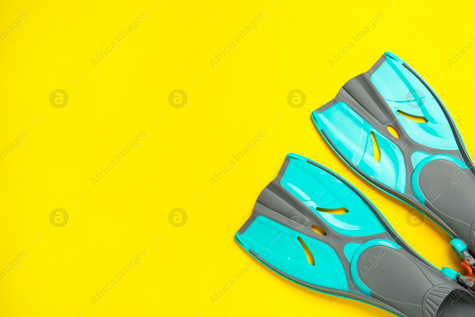 Photo of Pair of turquoise flippers on yellow background, flat lay. Space for text