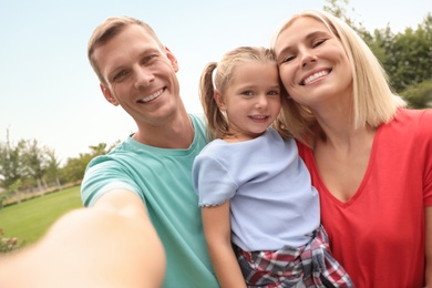 Photo of Happy family taking selfie in park on summer day