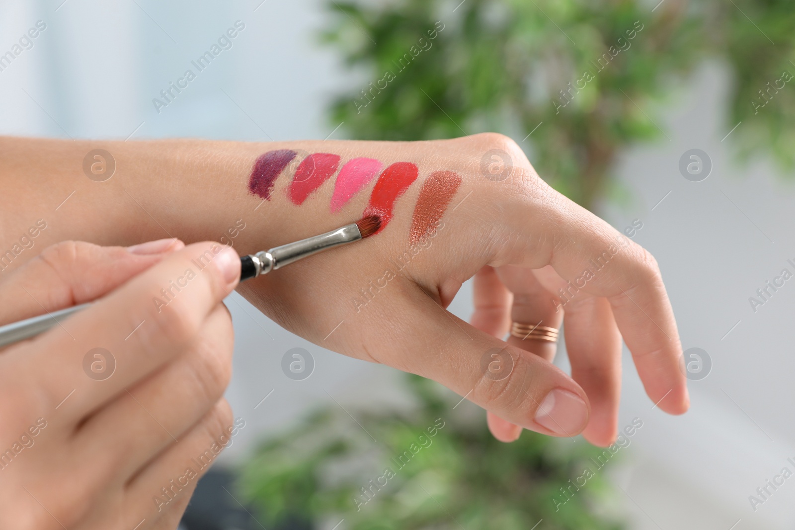 Photo of Woman testing and choosing lip gloss color on hand, closeup