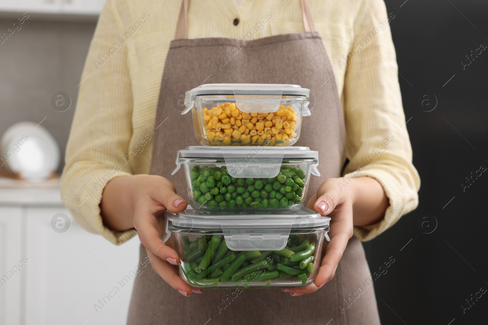 Photo of Woman holding containers with different fresh products in kitchen, closeup. Food storage