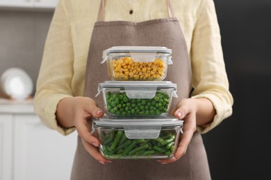 Woman holding containers with different fresh products in kitchen, closeup. Food storage