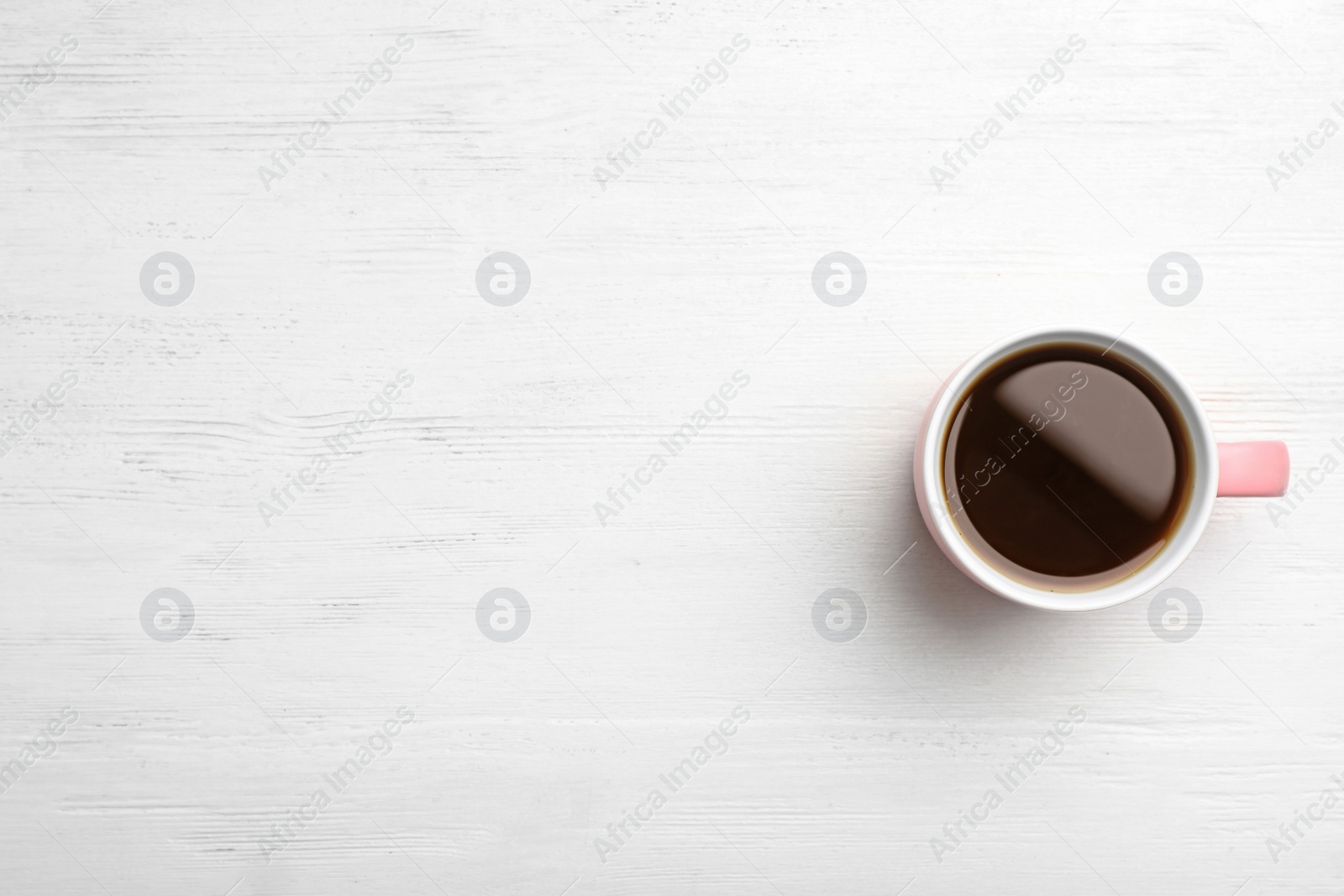 Photo of Ceramic cup with hot aromatic coffee on wooden background, top view