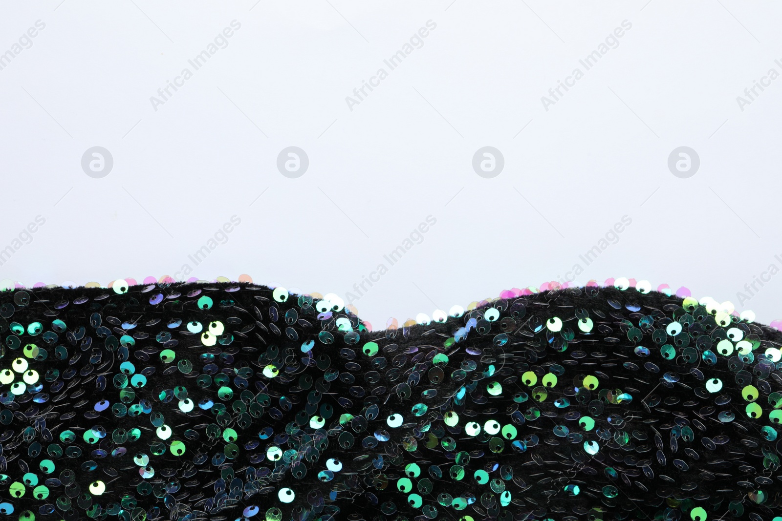 Photo of Dark shiny sequin fabric on white background, top view. Space for text