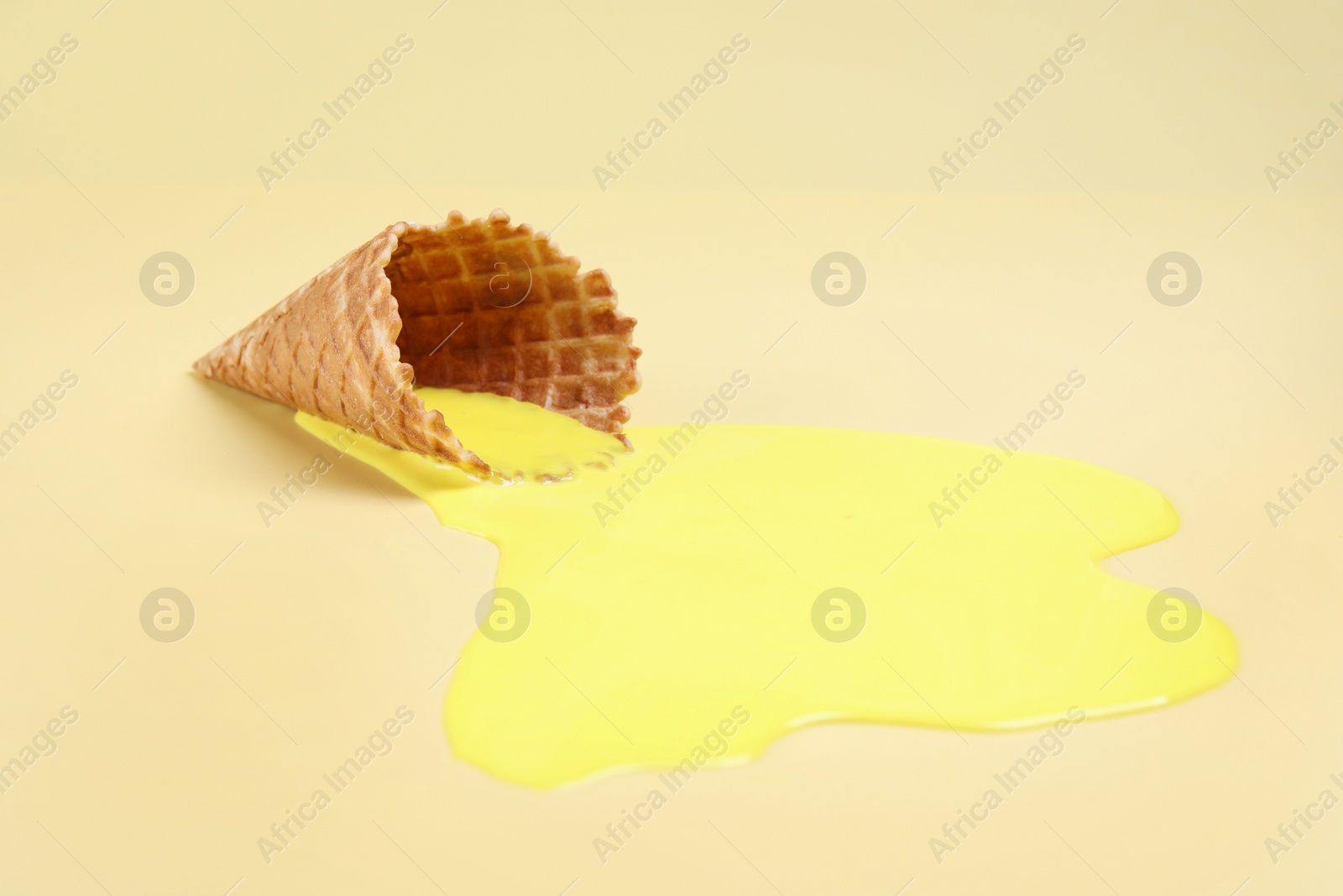 Photo of Melted ice cream and wafer cone on yellow background