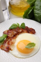 Photo of Fried egg, bacon and basil on table, closeup