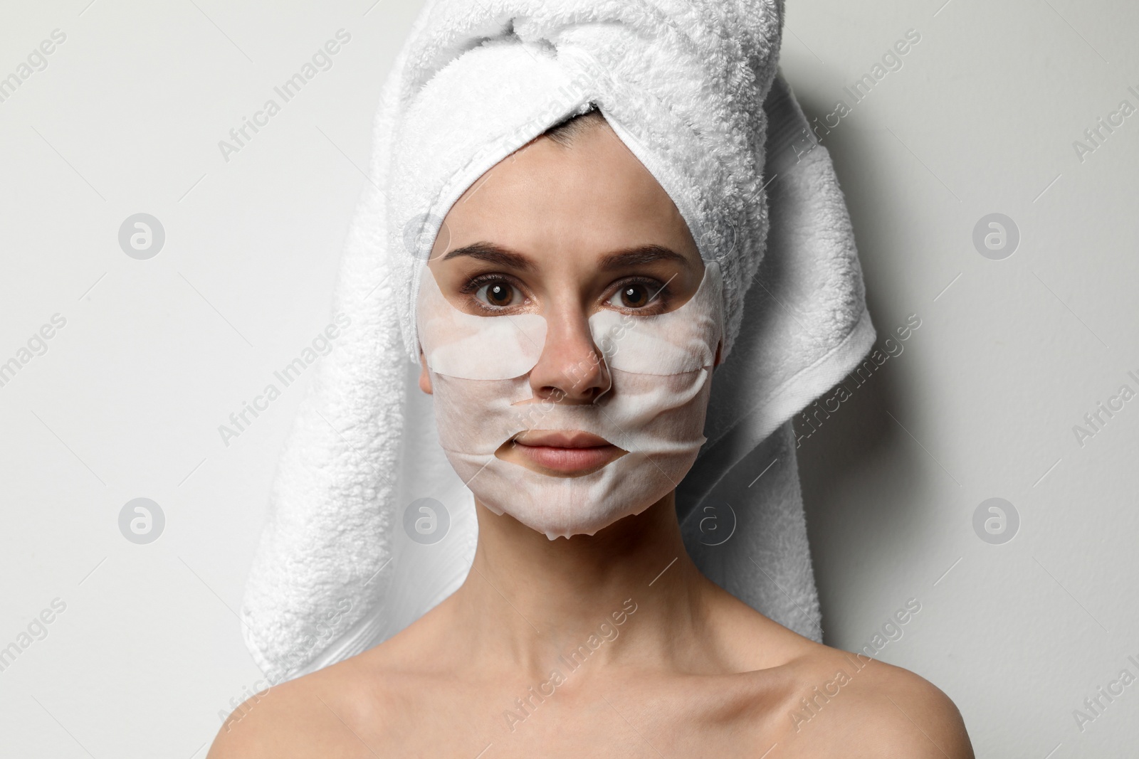 Photo of Beautiful woman with cotton face and eye masks against light background