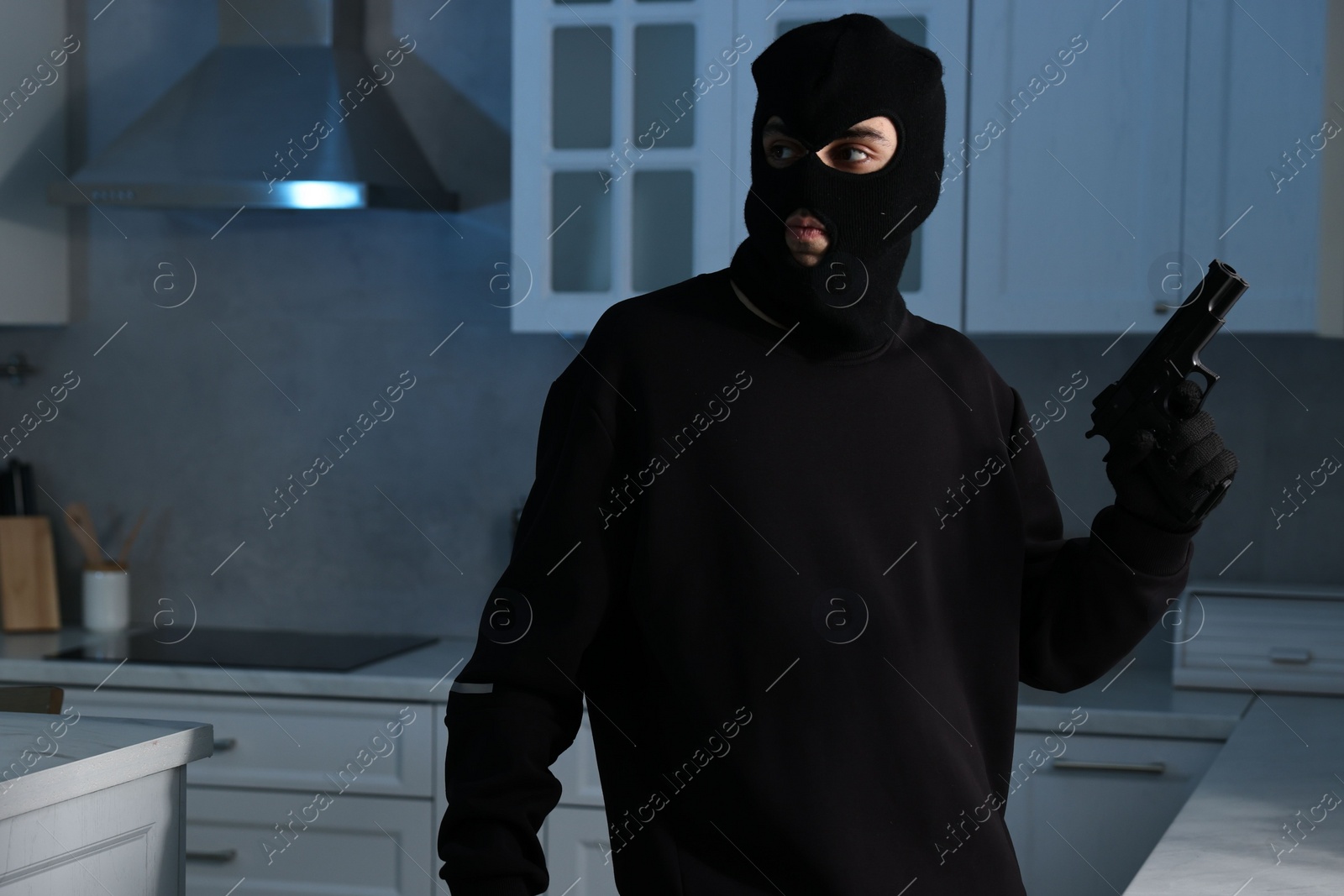 Photo of Thief wearing balaclava with gun in foreign house. Burglary