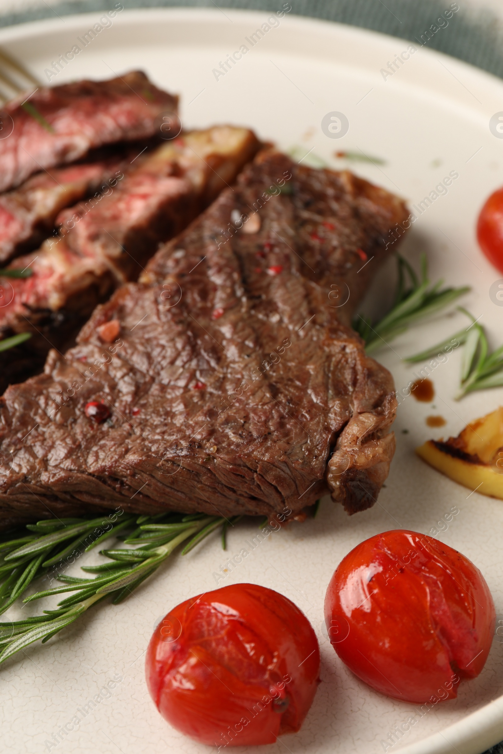 Photo of Delicious grilled beef steak, tomatoes and rosemary on plate, closeup