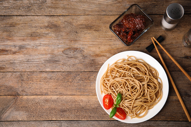 Photo of Tasty buckwheat noodles with chopsticks on wooden table, flat lay. Space for text