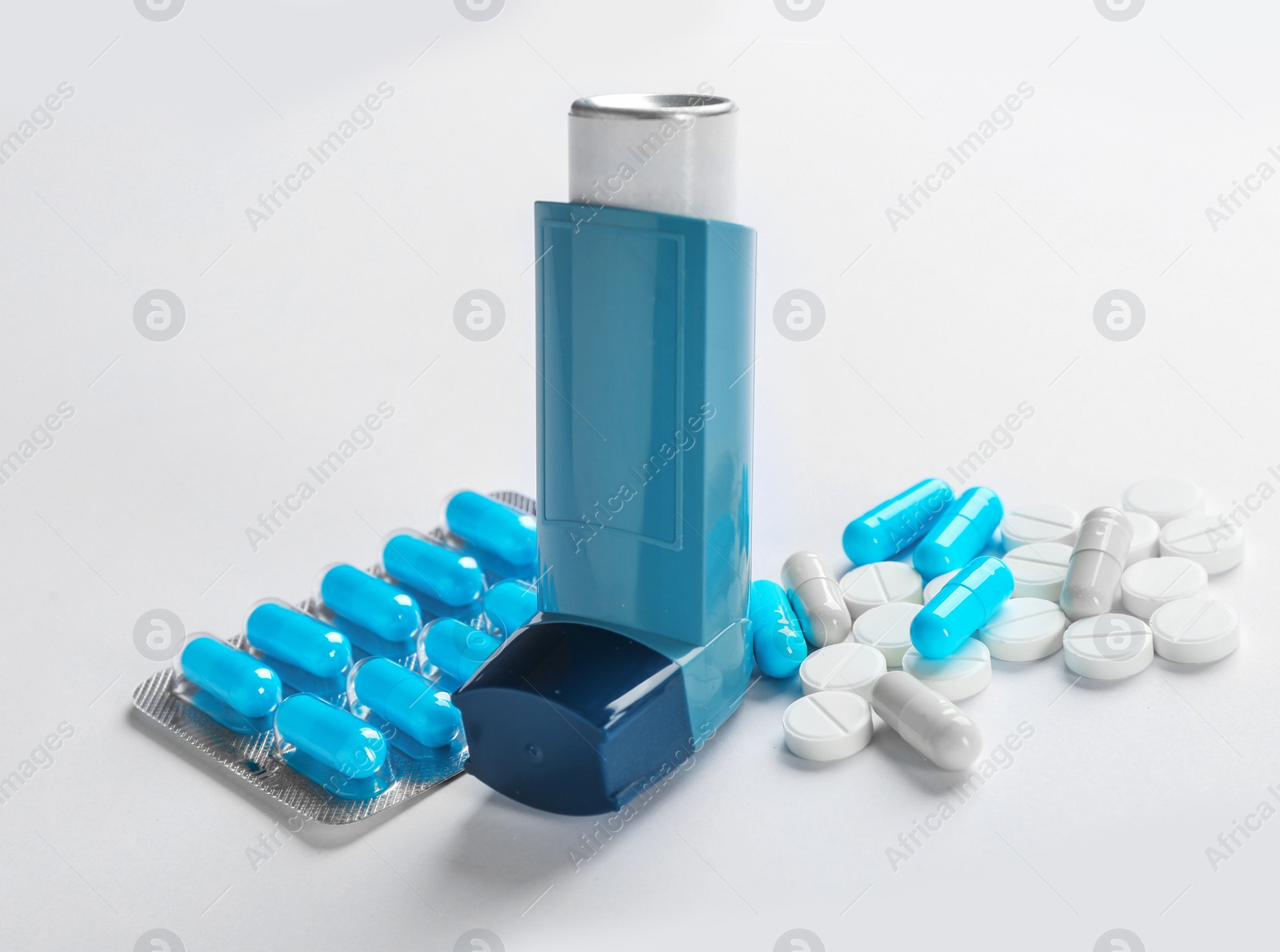 Photo of Asthma inhaler and pills on white background