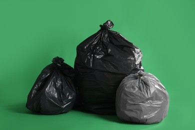 Trash bags full of garbage on green background