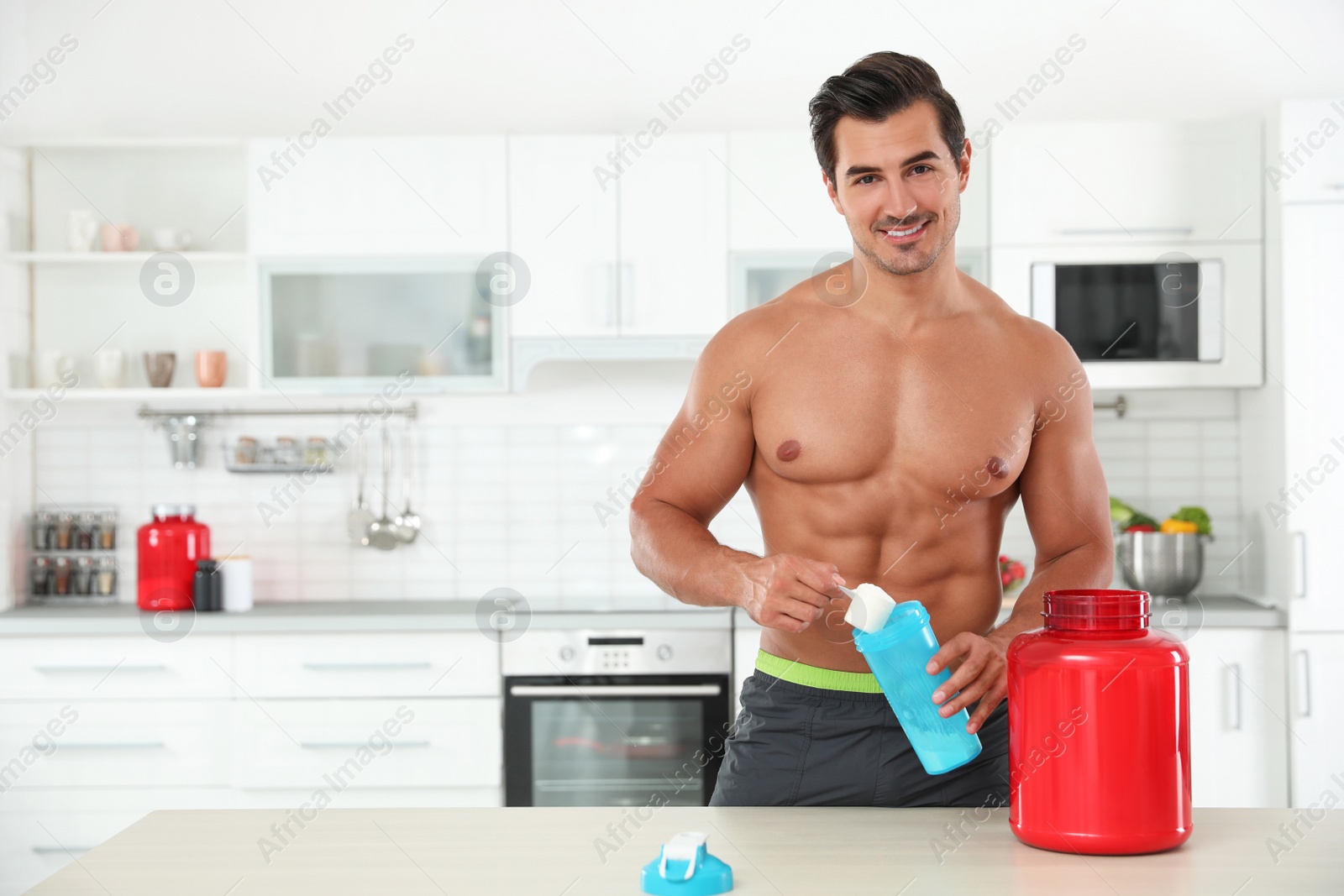 Photo of Young shirtless athletic man preparing protein shake in kitchen, space for text