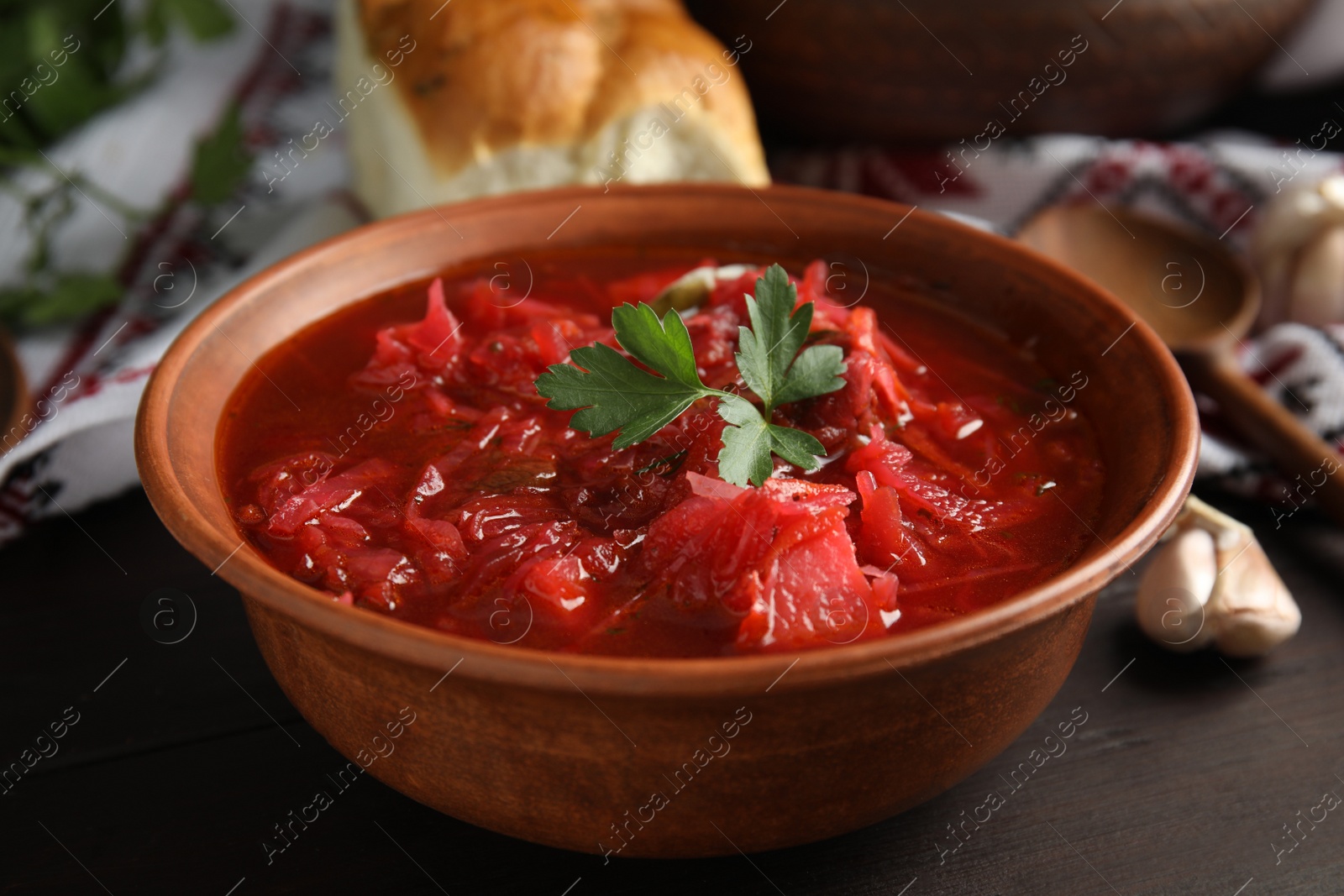 Photo of Stylish brown clay bowl with Ukrainian borsch served on wooden table, closeup