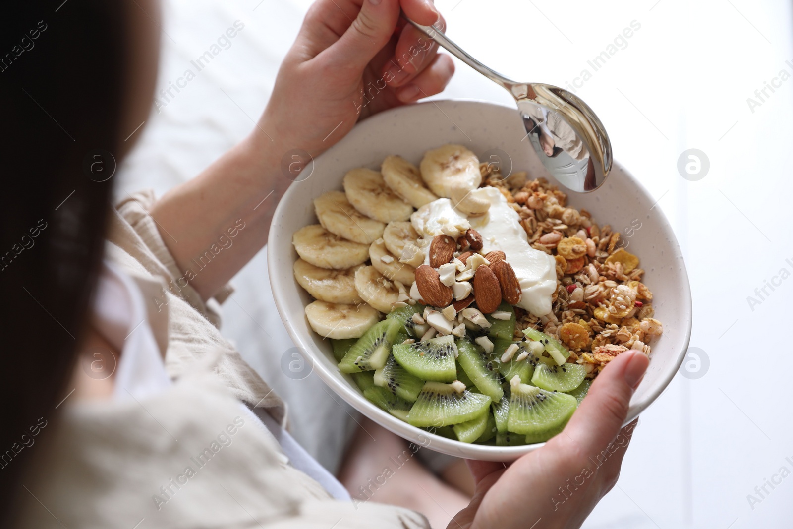 Photo of Woman eating tasty granola indoors, closeup view