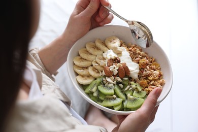 Photo of Woman eating tasty granola indoors, closeup view