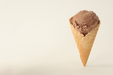 Photo of Delicious chocolate ice cream in waffle cone on white background. Space for text