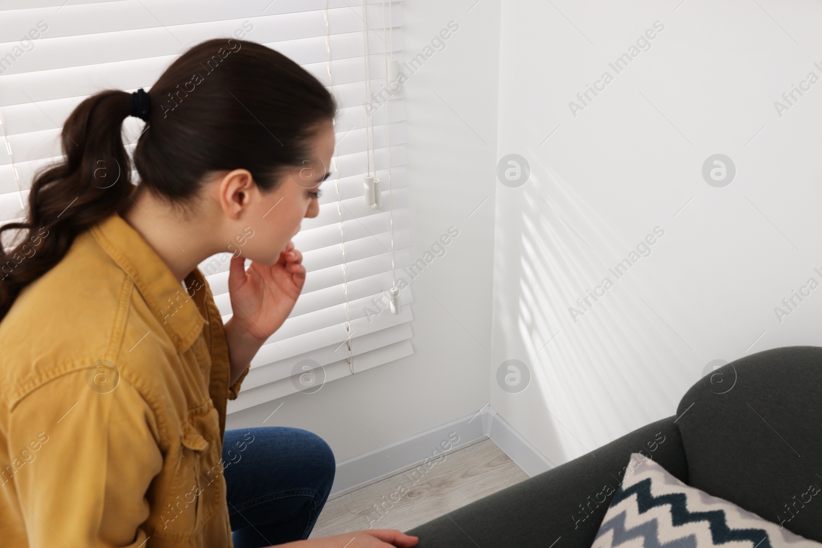 Photo of Young woman looking at white wall in room