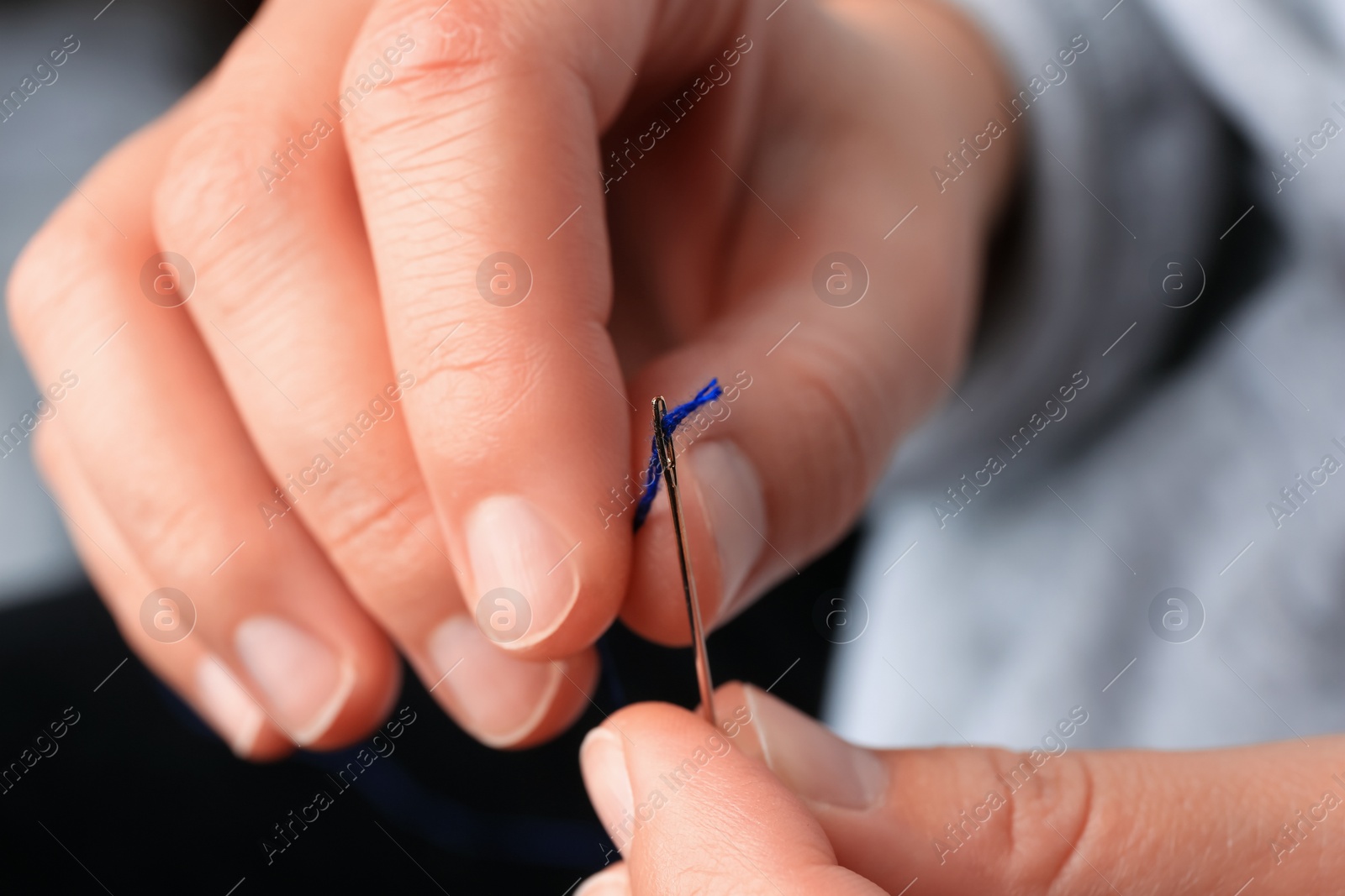 Photo of Closeup view of woman threading sewing needle