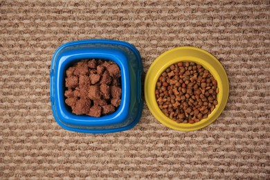 Dry and wet pet food in feeding bowls on soft carpet, flat lay