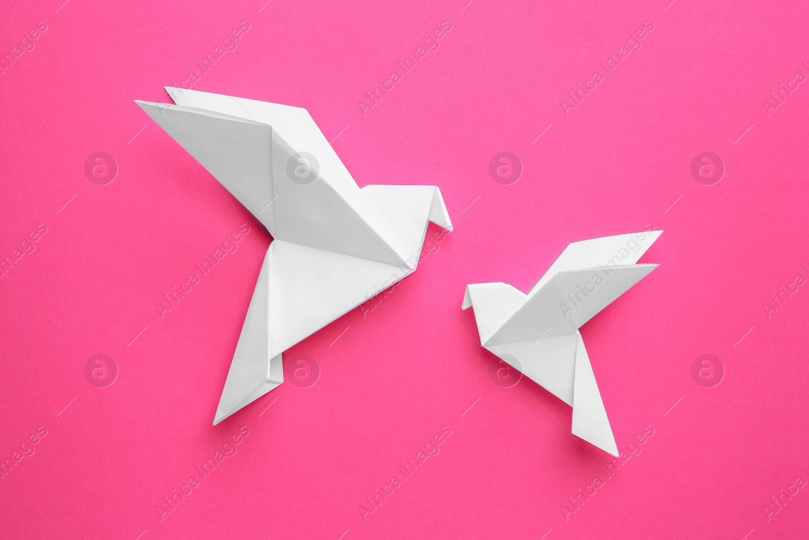 Photo of Beautiful white origami birds on pink background, flat lay