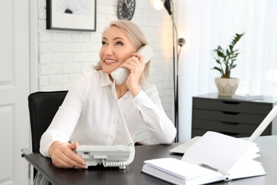 Mature woman talking on phone at workplace