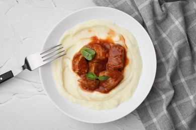 Photo of Delicious goulash served with mashed potato on white textured table, flat lay