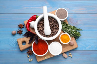 Flat lay composition with mortar and different spices on light blue wooden table