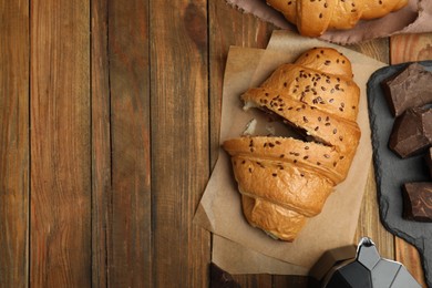 Flat lay composition with tasty croissants and chocolate on wooden table. Space for text