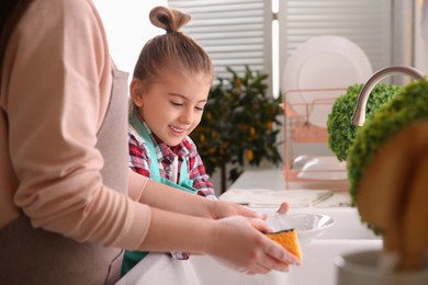 Photo of Mother and daughter washing dishes together in kitchen at home