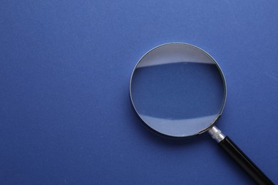 Photo of Magnifying glass on blue background, top view. Space for text