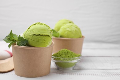 Photo of Paper cups with tasty matcha ice cream on white wooden table. Space for text