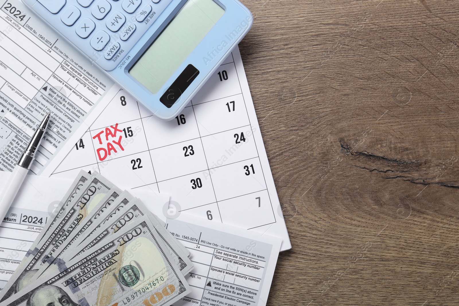 Photo of Calendar with date reminder about tax day, documents, money and calculator on wooden table, top view. Space for text