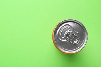 Energy drink in can on green background, top view. Space for text