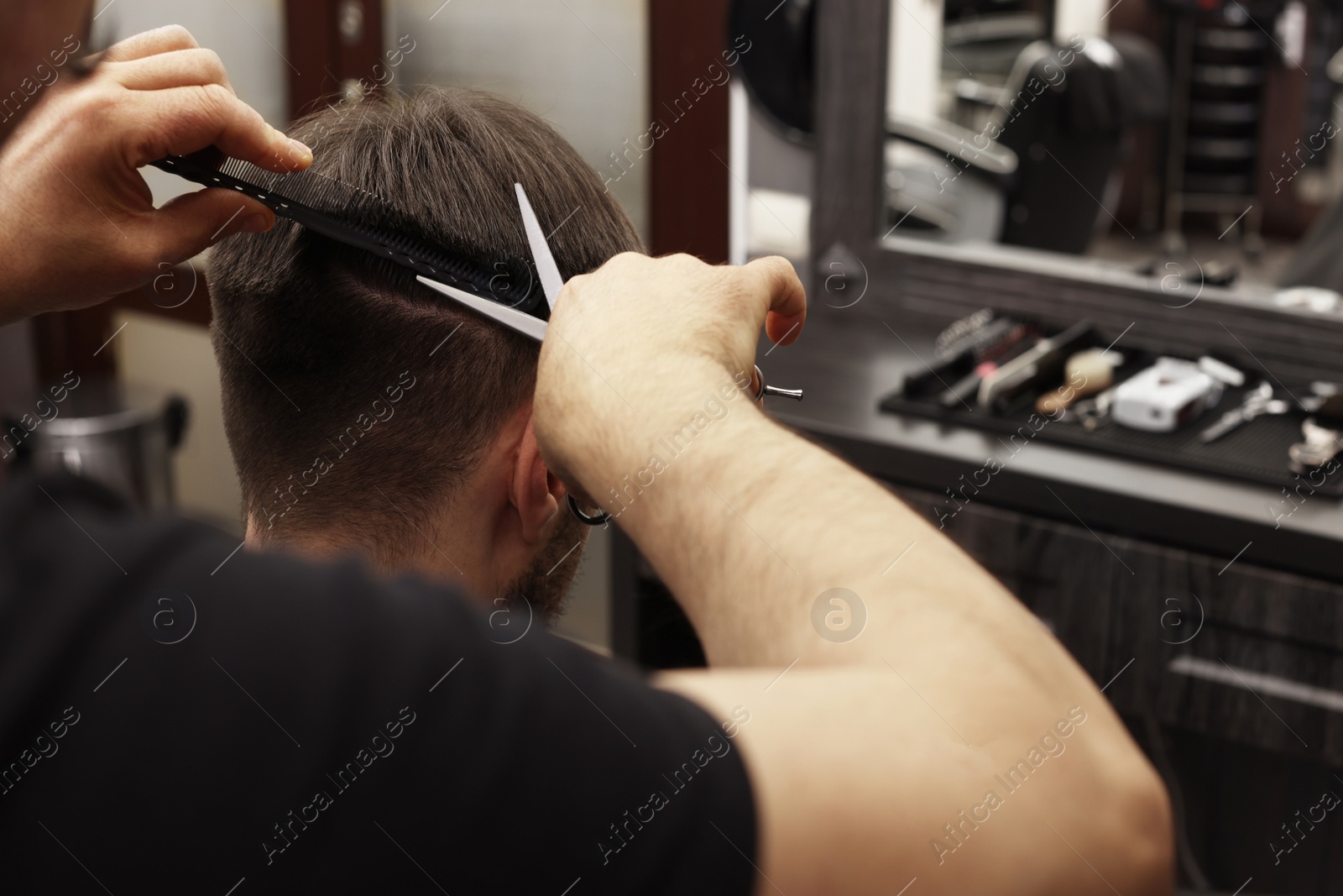 Photo of Professional hairdresser cutting man's hair in barbershop