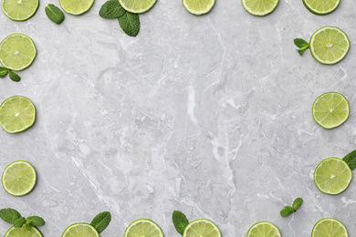 Photo of Flat lay composition with slices of fresh juicy limes on marble table. Space for text