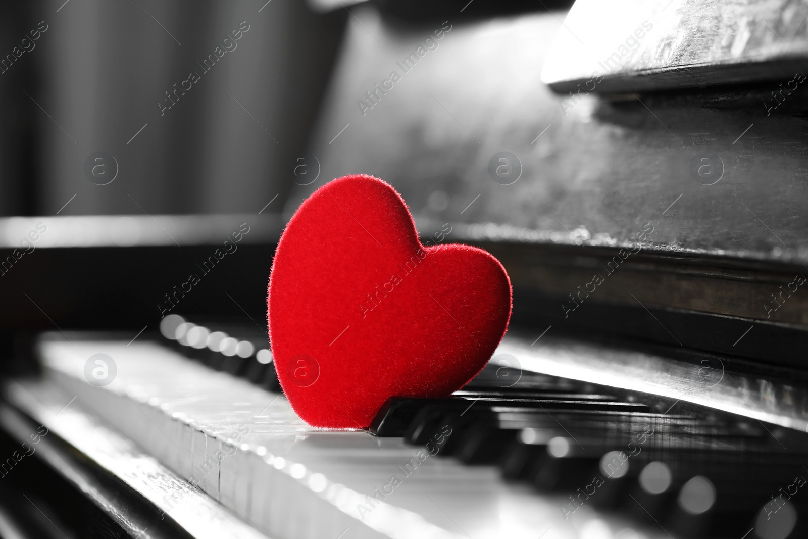 Photo of Small red decorative heart on piano keys, closeup. Space for text