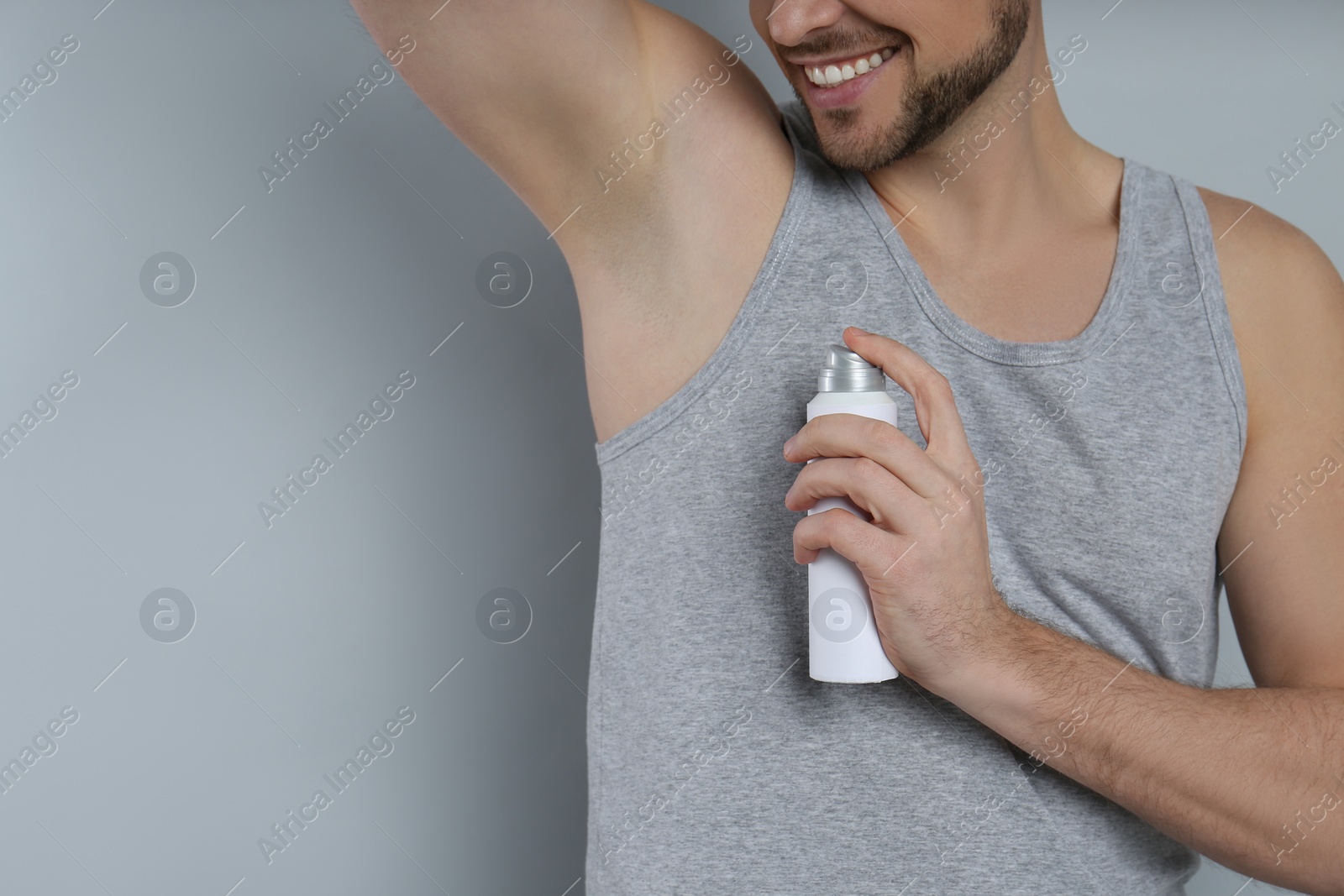 Photo of Man applying deodorant on grey background, closeup. Space for text