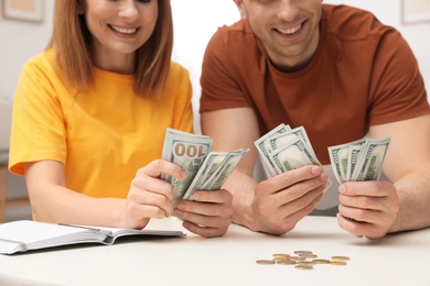 Photo of Couple counting money at table indoors, closeup