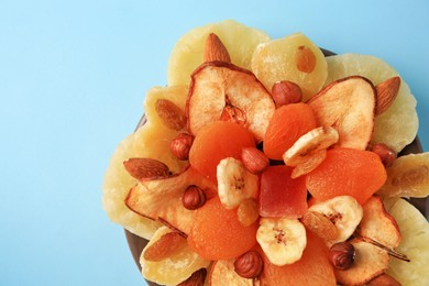 Photo of Mixed dried fruits and nuts on light blue background, top view. Space for text
