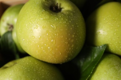 Fresh ripe green apples and leaves on wooden table, closeup