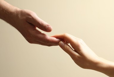 Man and woman holding hands together on beige background, closeup