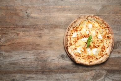 Delicious pizza with cheese and basil on wooden background, top view. Space for text